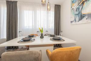 a white dining room table with chairs and a white tableablish at Apartman Holiday in Šibenik +8 photos