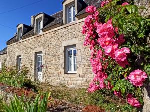 a stone house with pink flowers in front of it at Charmante longère bigoudène in Penmarch