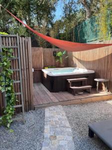 a wooden deck with a hot tub and a hammock at Magnifique T2 LUXE Jacuzzi & Piscine PRIVÉ PROCHE PLAGES ST AYGULF A PIEDS in Fréjus
