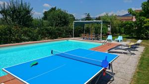 a pool with a ping pong table and chairs at Villa Cortinella in Marlia