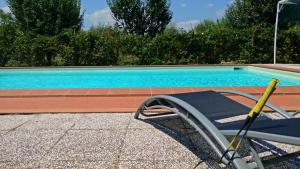 a swimming pool with a chair next to it at Villa Cortinella in Marlia