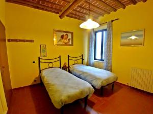 two beds in a room with yellow walls at Villa Cortinella in Marlia
