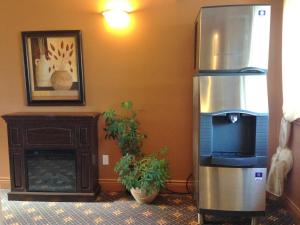 a stainless steel refrigerator in a room with a fireplace at Motel le Phare in Plessisville