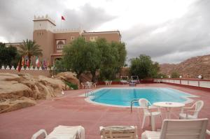 - une piscine avec des chaises et une table en face d'un bâtiment dans l'établissement Hotel Les Amandiers, à Tafraout