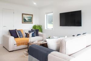 ein Wohnzimmer mit weißen Möbeln und einem Flachbild-TV in der Unterkunft Clareview Cottage in Rotorua