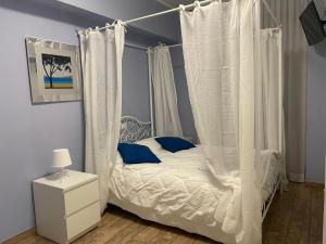a bedroom with a white canopy bed with blue pillows at Itaka in LʼAquila