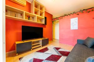 a living room with orange walls and a flat screen tv at Casa vacanze della Corte in Sestu