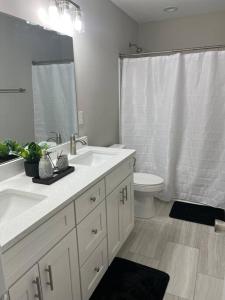 シャーロットにあるRockwell Retreatの洗面台2つとトイレ付きの白いバスルーム