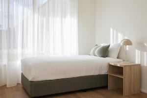 a bedroom with a bed with white curtains and a table at The Keith Motel in Tootgarook