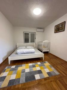 a bedroom with a bed and a crib and a rug at Vila Kulo in Svrake