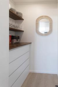 une cuisine avec des placards blancs et une fenêtre ronde dans l'établissement Okere Lakehouse Retreat, à Okere Falls 119 autres photos