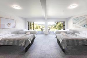 Cette grande chambre comprend 3 lits et une grande fenêtre. dans l'établissement Okere Lakehouse Retreat, à Okere Falls