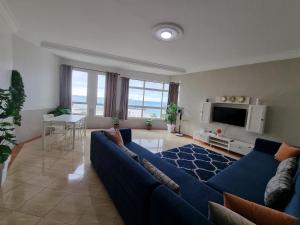 a living room with a blue couch and a tv at Beach View Apartment (Boulevard Mohammed VI) in Tangier