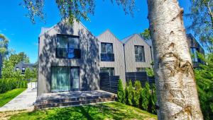 una casa con un árbol delante en Genys luxury apartamentai 1, en Palanga