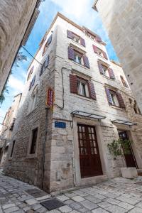 een hoog stenen gebouw met bruine deuren op een straat bij Villa Sv. Petar in Trogir