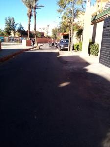 an empty street with palm trees and a building at Chambre hostel Assif in Marrakech
