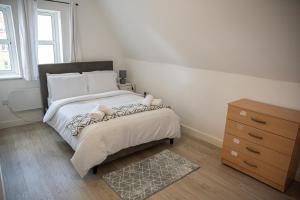 a bedroom with a large bed and a dresser at Luxury 2 bedroom apartment in Bedford in Bedford