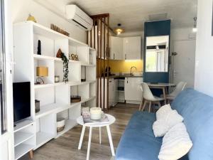 ein Wohnzimmer mit einer blauen Couch und einer Küche in der Unterkunft Le Tropico - Clim - Terrasse - Proche Polygone in Béziers