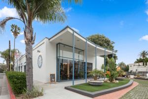 ein weißes Gebäude mit großen Fenstern und einer Palme in der Unterkunft ITH Santa Barbara Surf Hostel in Santa Barbara