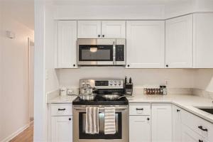 a white kitchen with a stove and a microwave at Serene, Spacious Home in Quiet Neighborhood with Fenced Yard in Aurora +20 photos