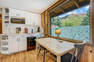 a kitchen with a table and a large window at Pikes Peak Stone Cottage - Hot Tub & Game Room in Cascade-Chipita Park