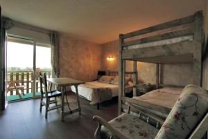 a bedroom with two bunk beds and a table and a balcony at Logis Hotel Restaurant Planes in Saillagouse