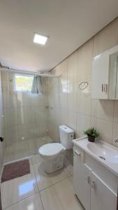 een witte badkamer met een toilet en een wastafel bij Apto Lírio da Paz- 3 Quartos com sacadas,espaçoso e de frente para avenida principal! in Piratuba +16 foto's