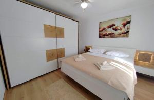 ein weißes Schlafzimmer mit einem Bett und einem Gemälde an der Wand in der Unterkunft Holiday house with a parking space Mundanije, Rab - 23396 in Rab