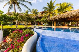 a swimming pool at a resort with palm trees and flowers at Casa Manzanillo - Point Room - Ocean Front Room at Exceptional Beach Front Location in Troncones