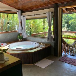 bañera grande en una habitación con ventanas en Chalé aconchego, en Santo Antônio do Pinhal