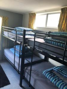 a room with three bunk beds and a window at Alpine Lodge Queenstown in Queenstown