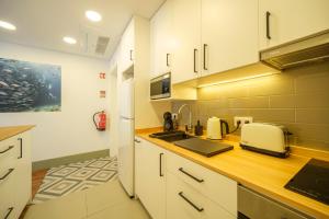 Una cocina con gabinetes blancos y encimera. en Azimute 4, en Angra do Heroísmo