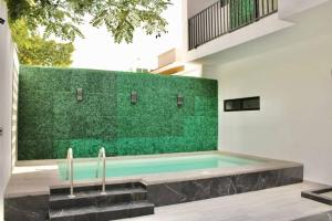 a swimming pool with a green wall in a house at Hotel boutique 1A Lomas Sense in Mazatlán