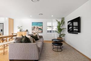 a living room with a couch and a table at Seas the Day Comfort and Spa in Mount Maunganui