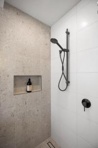 a bathroom with a shower with a bottle on a shelf at Seas the Day Comfort and Spa in Mount Maunganui +27 photos