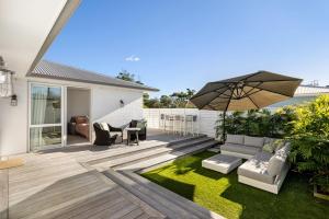 a backyard with a patio with an umbrella at Seas the Day Comfort and Spa in Mount Maunganui