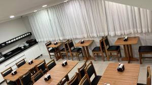 a restaurant with wooden tables and chairs and curtains at Hotel Quintino - No Coração de São Paulo, 2 Min do Metrô Sé, 10 Min do Brás, 5 Min da 25 de Março e Estacionamento no Local Grátis in São Paulo
