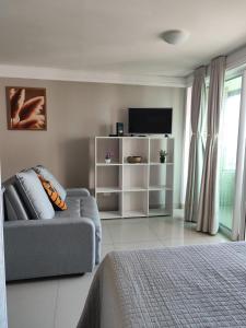 a living room with a couch and a tv at VISTA para o MAR e o PÔR DO SOL - MAR BELLO PLAZA in Cabedelo