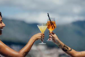 two women holding up drinks in their hands at All'oro in Njivice