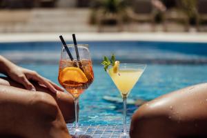 two cocktails sitting on a table next to a swimming pool at All'oro in Njivice