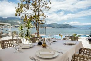 a table with white plates and glasses and a view of the water at All'oro in Njivice
