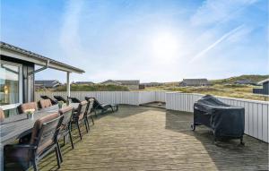a deck with a long wooden table and chairs at Holiday Home Bjerregårdsvej Hvide Sande Denm in Bjerregård