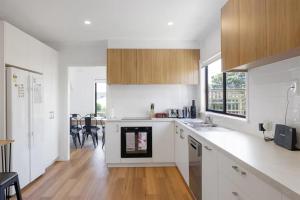 a kitchen with white counters and wooden cabinets at Sommerhuset by Ready Set Stay in Cowes +10 photos