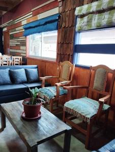 a living room with chairs and a table and a couch at Cabaña Choroy dentro del pueblo, cercano a playas in Licán Ray