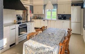 una cucina con tavolo e sedie e una cucina con mobili bianchi di Beautiful Home In Södra Vi With Wifi a Södra Vi