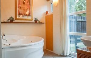 a bathroom with a tub and a sink and a window at Holiday Home Granvej Rømø Ii in Bolilmark