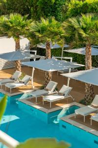 a group of chairs and umbrellas next to a pool at Resort Miramonti in Forte dei Marmi
