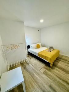 a bedroom with a bed with a yellow blanket at Casinha da Patricia in Nazaré