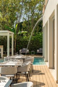 a pool with tables and chairs and a fountain at Resort Miramonti in Forte dei Marmi