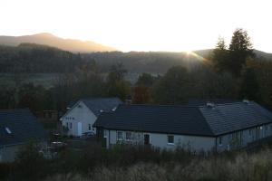 un grupo de casas con la puesta de sol en el fondo en BCC Loch Ness Hostel, en Bearnock